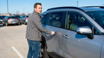 Man locking his grey SUV car rental in a parking lot to prevent theft and keep valuables safe.