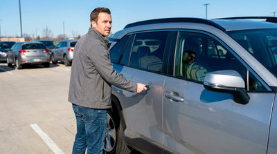 Man locking his grey SUV car rental in a parking lot to prevent theft and keep valuables safe.