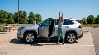 Woman stretching at a rest stop next to a silver Toyota SUV car rental to avoid drowsy driving.