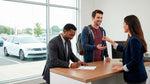 Two men at a car rental counter signing the agreement to rent a car for another driver.