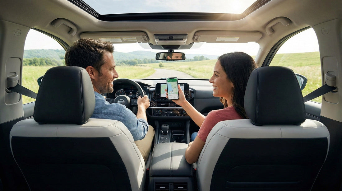 A couple in a Nissan Pathfinder on a rural road trip; the passenger is holding a smartphone displaying a navigation map.
