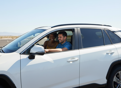 Couple driving a red convertible car hire on a Las Vegas boulevard, exploring the city on the cheapest car rental days of the week.
