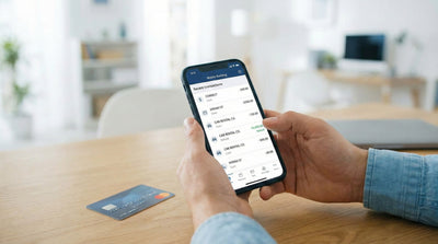 Person viewing a car rental refund transaction on a smartphone banking app screen indoors.