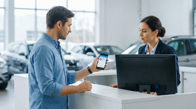 A customer showing a digital driver's license on a smartphone to a car rental agent at the pickup counter.
