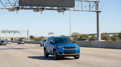 A modern car hire vehicle driving on a multi-lane Texas highway towards an express lane toll sign