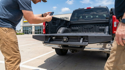 A man inspects the tailgate of a white pickup truck car rental on a sunny day in rural Texas