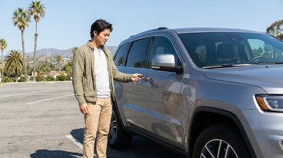A driver looks at a keyless remote for their car hire, parked on a sunny street in California