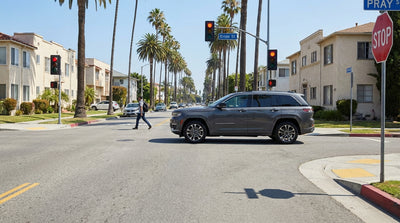 A car hire stops for a person at a crosswalk on a sunny street in Los Angeles