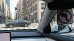 A car hire vehicle waiting at a red traffic light on a busy street corner in New York City