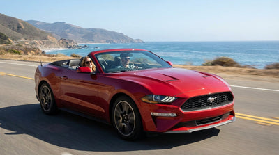 A red convertible car rental driving along the scenic Pacific Coast Highway in California