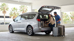 Several suitcases packed into the open trunk of a car rental parked on a sunny street in Orlando