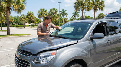 A modern car rental parked under palm trees on a sunny street in Florida