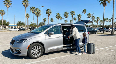 A father installs a child's booster seat into a car hire vehicle for a family road trip in Texas