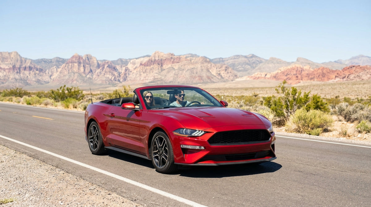 A convertible car hire drives down the neon-lit Las Vegas Strip at night past famous casinos and glowing signs