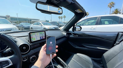 A person's hands connecting an iPhone to the dashboard display of their car rental in San Francisco