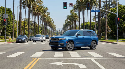 A car hire drives on a sunny, palm-lined street in Los Angeles approaching a traffic light intersection