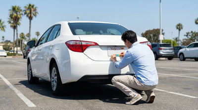 A driver's hand points to the current registration tags on the license plate of a California car hire