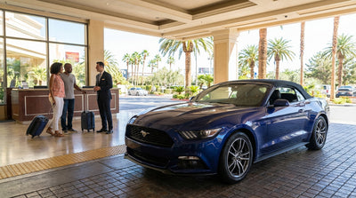 A sporty red convertible car hire parked along the Las Vegas Strip with the neon city lights glowing at dusk