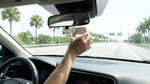 A white car rental driving under a SunPass electronic toll gantry on a sunny highway in Florida