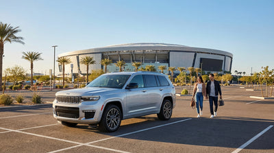 A car rental parked with a view of the glowing Allegiant Stadium against the Las Vegas skyline at dusk