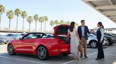 Traveler with luggage walking past a row of vehicles at a Miami car hire center