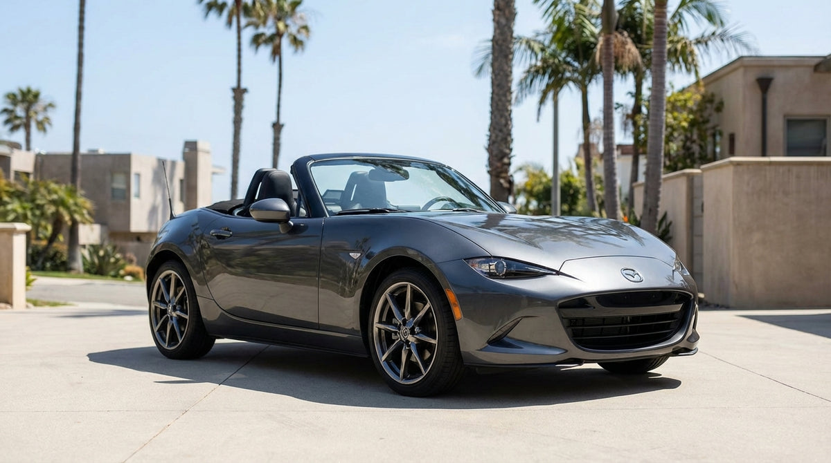 A silver convertible car rental driving along a sunny, winding coastal highway in California
