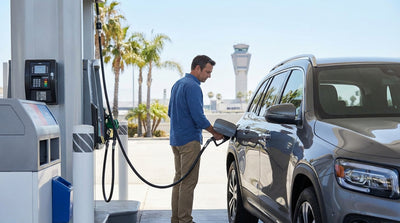 A car rental driving on a freeway in Los Angeles with signs for LAX airport under a clear blue sky