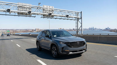 A car hire drives across a bridge toward the Philadelphia, Pennsylvania skyline at sunset