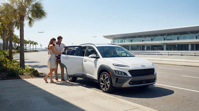 A father adjusts a child seat in the back of a car rental while parked in a sunny lot in Orlando