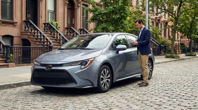 A car rental driving across the Brooklyn Bridge with the lower Manhattan, New York skyline in the background