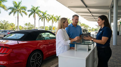 A convertible for car hire driving down a sunny coastal road lined with palm trees in Florida