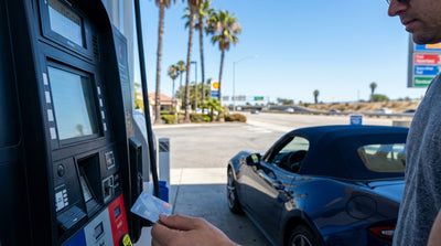 A person driving a convertible car rental down a sun-drenched road lined with palm trees in California