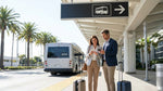Travelers with luggage waiting for a car rental shuttle outside LAX Terminal 2 in Los Angeles