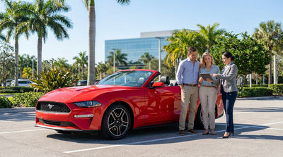 A convertible car rental driving down a sunny coastal highway in Florida lined with palm trees