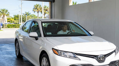 A car wash attendant drives a clean modern car hire out of a sunny wash bay in Florida
