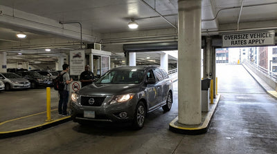 A large SUV car hire driving through busy traffic in New York City, past yellow cabs and skyscrapers