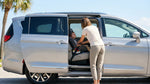 Mother buckling a toddler into a safety seat in the back of a Florida car rental parked near sunny palm trees