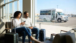 A car rental shuttle bus waits for travelers with luggage outside an airport in the United Estates