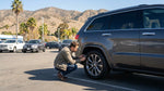 A white SUV car hire driving on a winding road through the scenic mountains of California