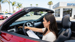 Driver's hands on the steering wheel of a car rental in California with a dashboard warning light illuminated