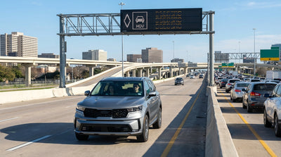 A car hire drives on a busy Houston, Texas freeway with a diamond-marked HOV lane to the left