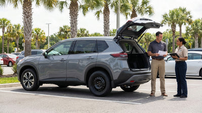 A driver changing a flat tire for a temporary spare on a car hire vehicle on a sunny Orlando roadside