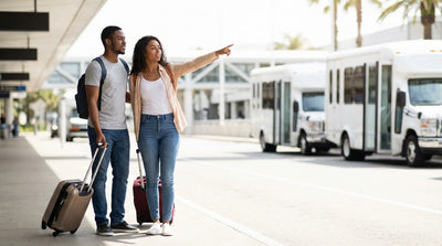 Travelers with luggage wait for a car rental shuttle bus at the LAX-it pickup lot in Los Angeles
