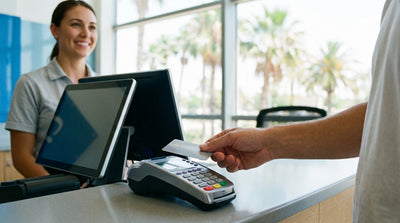 A person's hand holding a credit card at a car hire counter in a sunny Florida airport terminal