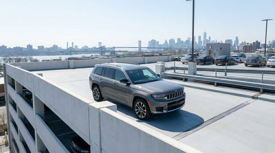 A car hire drives over a bridge toward the New York City skyline through afternoon traffic