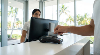 A red convertible car hire parked on Ocean Drive in Miami with palm trees and art deco buildings