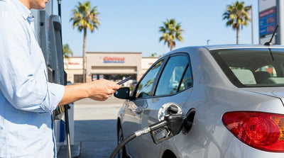 A convertible car rental driving down a sunny, winding coastal highway in California