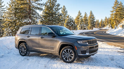 A car hire vehicle drives on a winding road through a snowy mountain pass in California