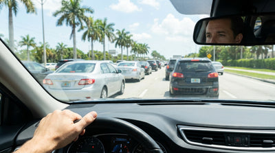 A car rental dashboard with the temperature gauge in the red, stuck in a traffic jam on a sunny Florida highway