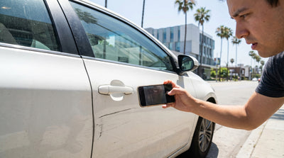 A long key scratch is visible on the side of a dark car hire parked on a street in Los Angeles